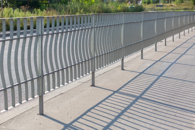 A metal fence near the road on the street protects the sidewalk