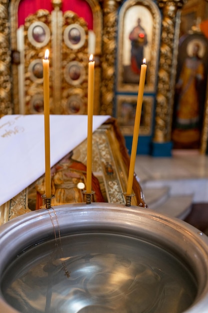 Metal font for christening in the church with candles