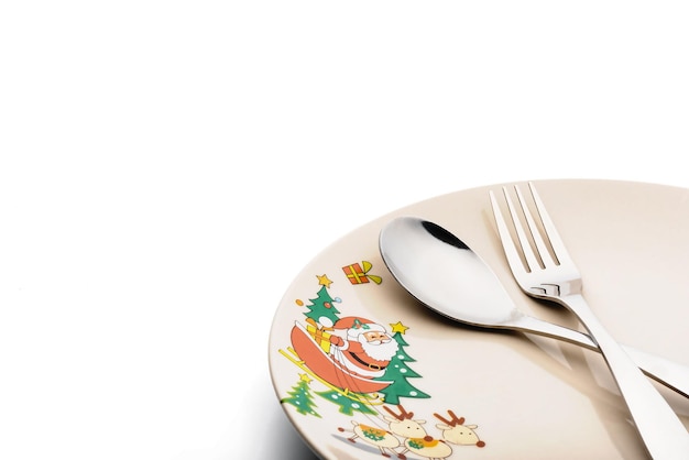 Metal fork and spoon lay on christmas pattern dish isolated on white background