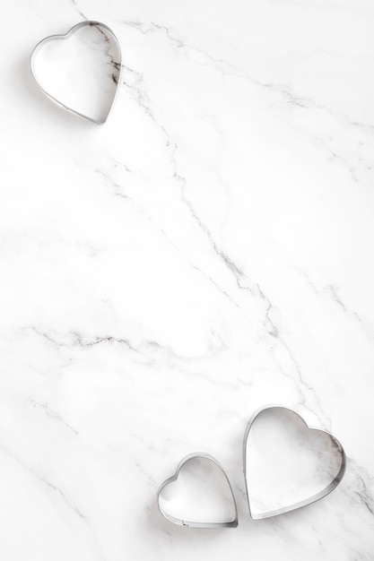 Metal forms for heart shaped cookies on marble table. Concept cooking with love, cooking for your loved ones, baking for valentines day. Copy space. Top view