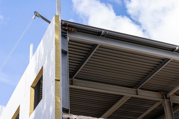 The metal frame of the new building with insulation and sandwich panels