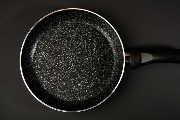 Photo metal frying pan ceramic coating with nonstick coating kitchen utensils on a black background cooking for chefs in the kitchena place for the textxa