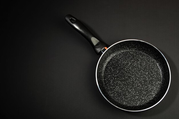 Photo metal frying pan ceramic coating with nonstick coating kitchen utensils on a black background cooking for chefs in the kitchena place for the textxa
