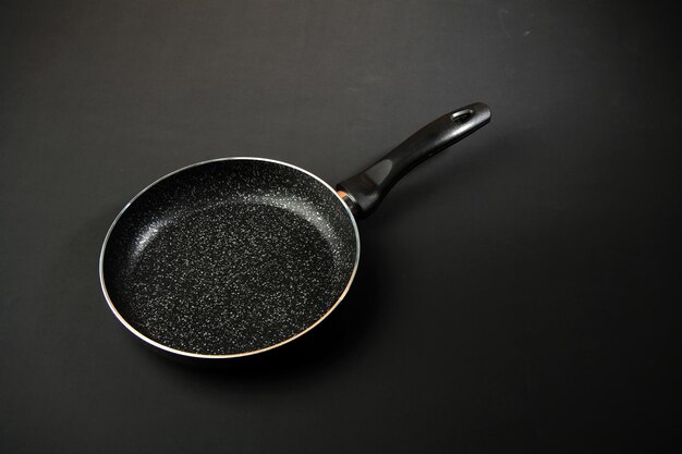 Фото Металлическая сковорода керамическое покрытие с антипригарным покрытием кухонная утварь на черном фоне готовим для поваров на кухнеместо для текстаxа