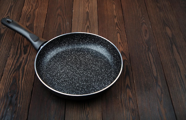 Photo a metal frying pan ceramic coating with nonstick coating kitchen utensilson a wooden background