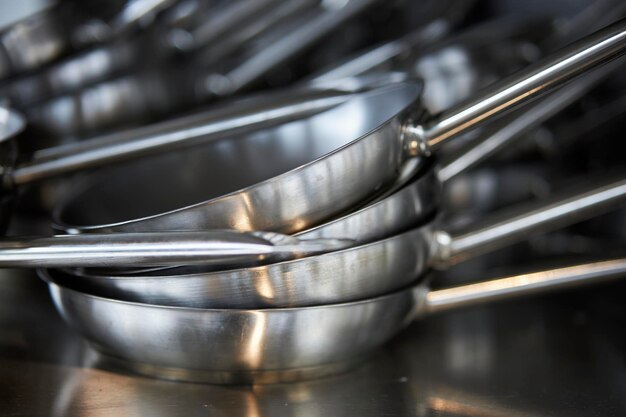 metal frying pans on a shelf in the kitchen a stack of metal pans in the kitchen on a shelf