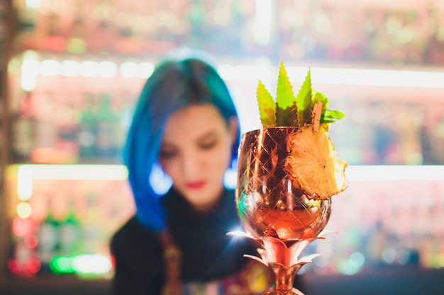 Metal glasses of fresh summer cocktails decorated with fruit and fume on the bar counter.