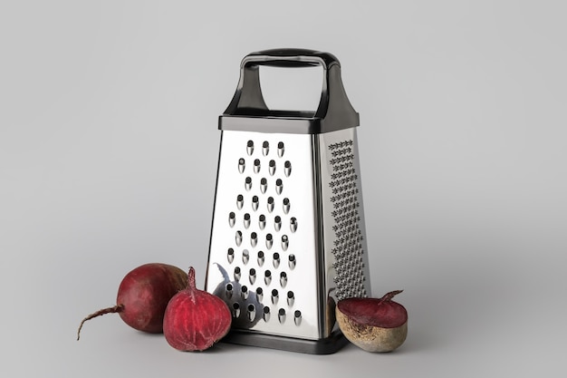 Metal grater and beetroots on grey background