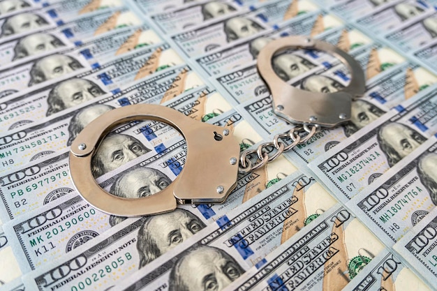 Металлические наручники на фоне концепции взяточничества или преступных денег наличной валюты в долларах США