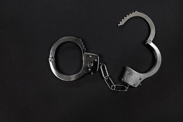 Metal handcuffs on black background