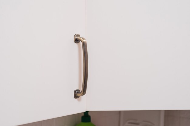 The metal handle on the kitchen cabinet door.