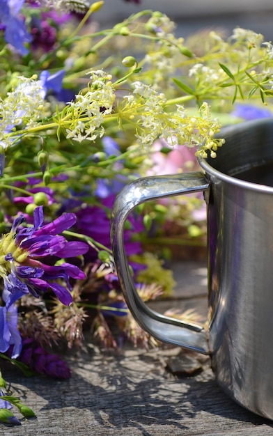 Metal handle tourist mugs with purple and white flowers on wooden table