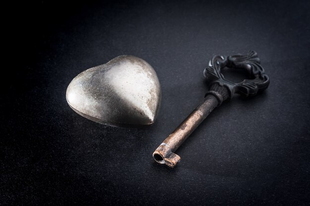 Metal heart with key on dark background, Metaphor love concept.