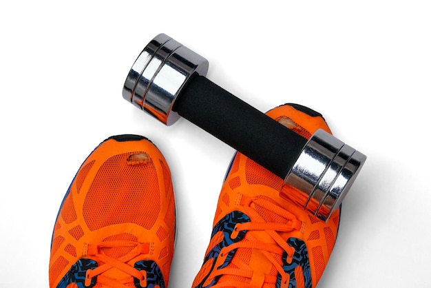 Metal heavy dumbbell fell on a leg in orange torn sneakers on a white background