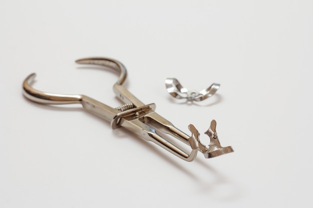 Metal instrument for dental treatment. Dental tongs for clasps on white background. Medical tools. Shallow depth of field.