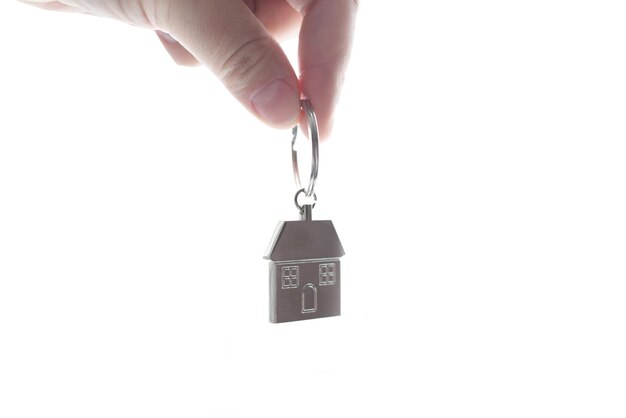 Metal keychain in the form of a house in a female hand, close-up