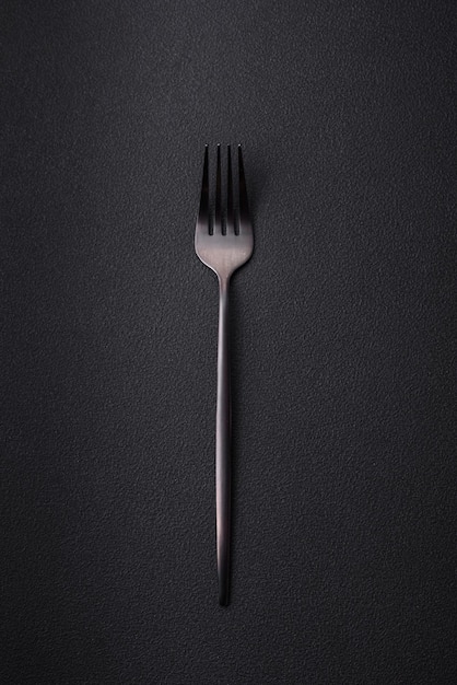 Metal kitchen fork on a dark textured concrete background