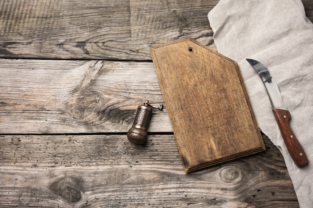 Metal kitchen knife and wooden cutting board on a table made of wooden boards, top view