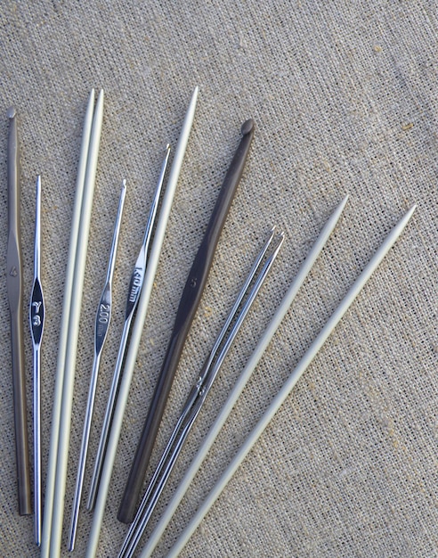 Metal knitting needles and hooks on a linen tablecloth. The concept of needlework, hobby.