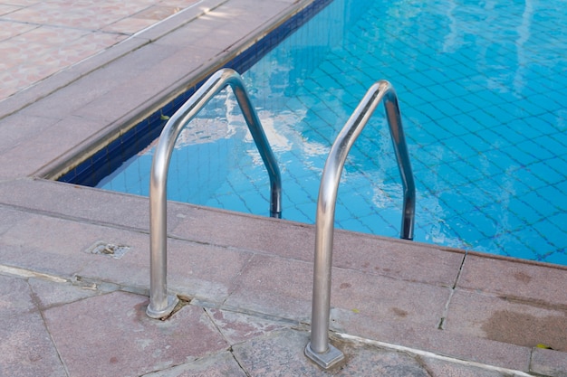 Metal ladder to descend to the swimming pool. Clear turquoise water in the pool.