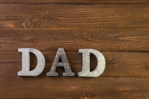 Metal letters DAD on a painted wood background.