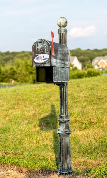 우편 또는 부재자 투표 용지로 투표하기 위한 개념으로 I Voted 스티커가 있는 시골 가정용 금속 우편함