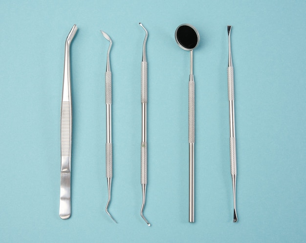 Metal medical items of the dentist on a blue background, flat lay