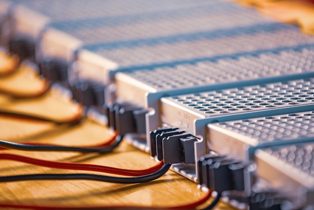 Metal mesh cases of power supply and wires are on a wooden table at the production of high-tech computers. Concept of high technology and industrial production