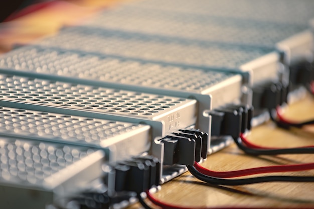 Metal mesh cases of power supply and wires are on a wooden table at the production of hightech computers