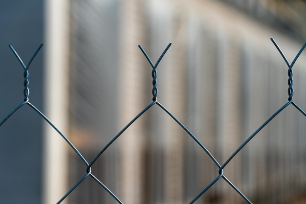 Metal mesh fence closeup abstract and blurred focus\
construction site is not of focus behind the iron fence for\
background and street art decoration