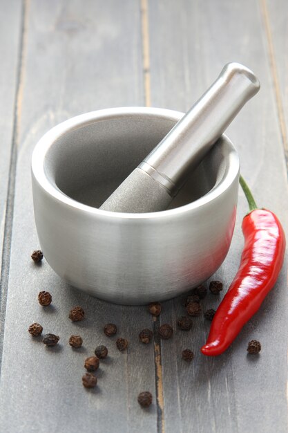 Metal mortar and pestle with pepper on wooden background