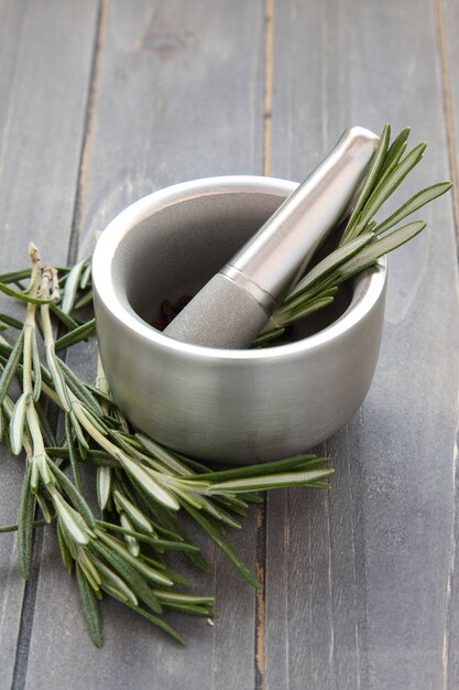 Metal mortar and pestle with rosemary on wooden background