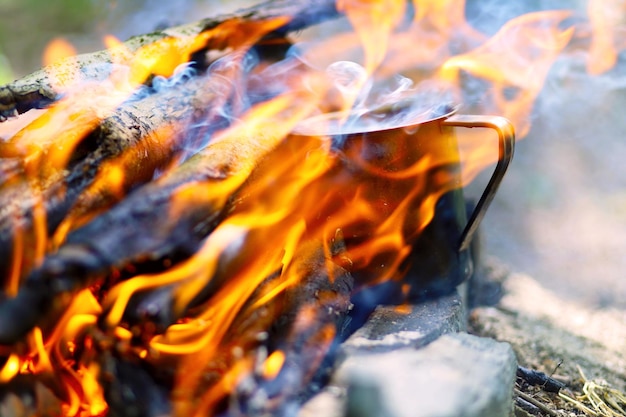 Photo metal mug on fire in the forest