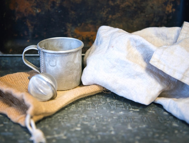 Metal mug or stainless cup with tea egg behind the cotton white towel creative rustic vintage style