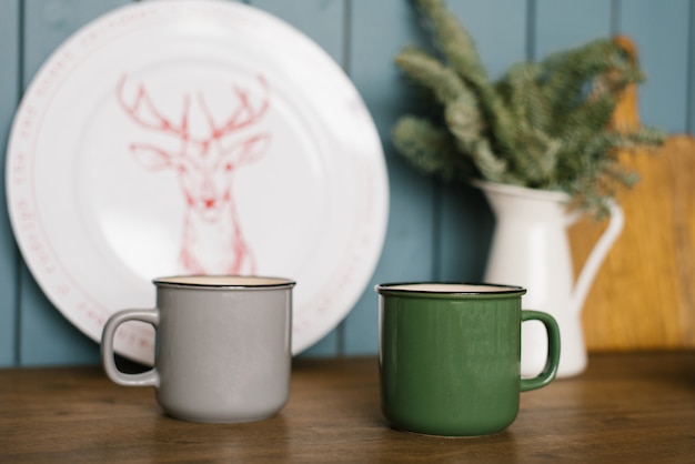 Metal mugs of gray and green are on the countertop of the kitchen