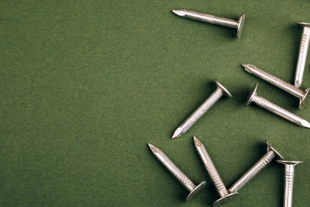 Metal nails close up, lots of nails on a green background.