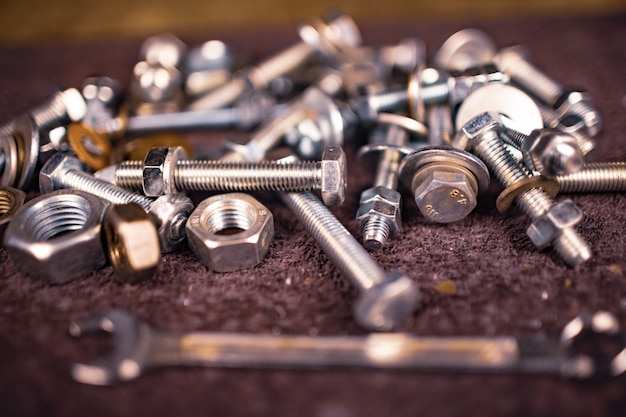 Metal nuts bolts and a wrench lie on the work table of the assembler