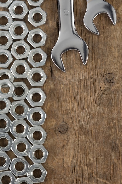 Metal nuts and wrench tool on wood wall texture