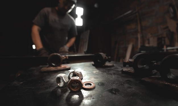 Metal parts tools and nuts on an iron table closeup against the background of a home workshop Making metal products with your own hands