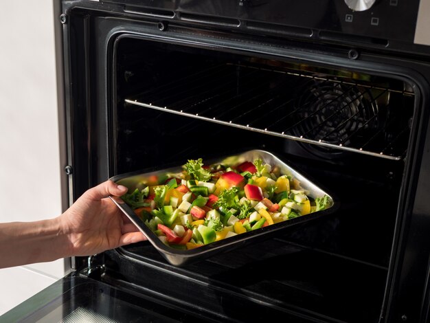 Metal plate with vegetables in oven