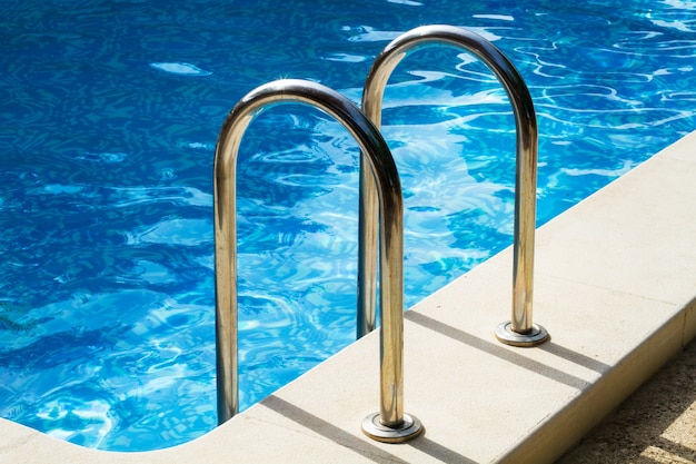 Metal pool ladder on the top of a swimming pool with transparent water