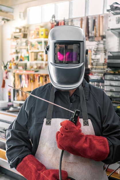 Photo metal processing with man using welding machine for steel seam helmet and glove