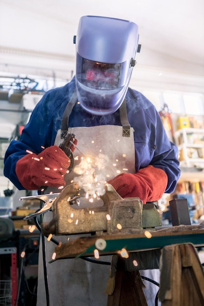 Lavorazione dei metalli con un uomo che utilizza una saldatrice per cucitura in acciaio abbigliamento speciale