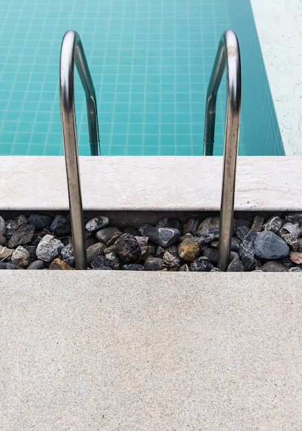 Metal rail of the ladder in a clear swimming pool