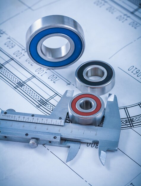 Metal rolling bearings and slide caliper on blueprint construction concept