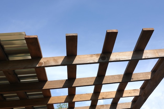 Metal roof mounting on brown wooden gazebo crate on a sunny summer day bottom up view outdoors