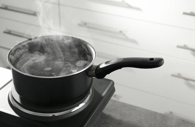 Photo metal saucepan on electric stove in kitchen