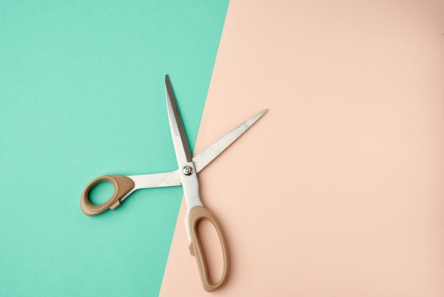 Photo metal scissors with a plastic handle on a green-beige background