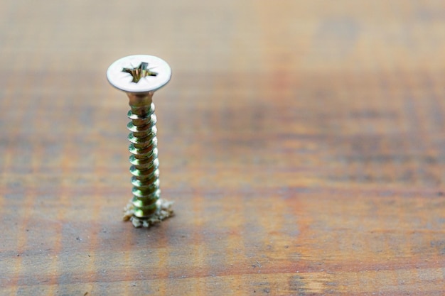 Foto la vite di metallo è stata inserita nella superficie della tavola di legno con il concetto di riparazione della casa o dell'officina del cacciavite