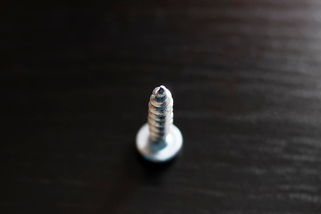 Metal screw on a wooden table top view